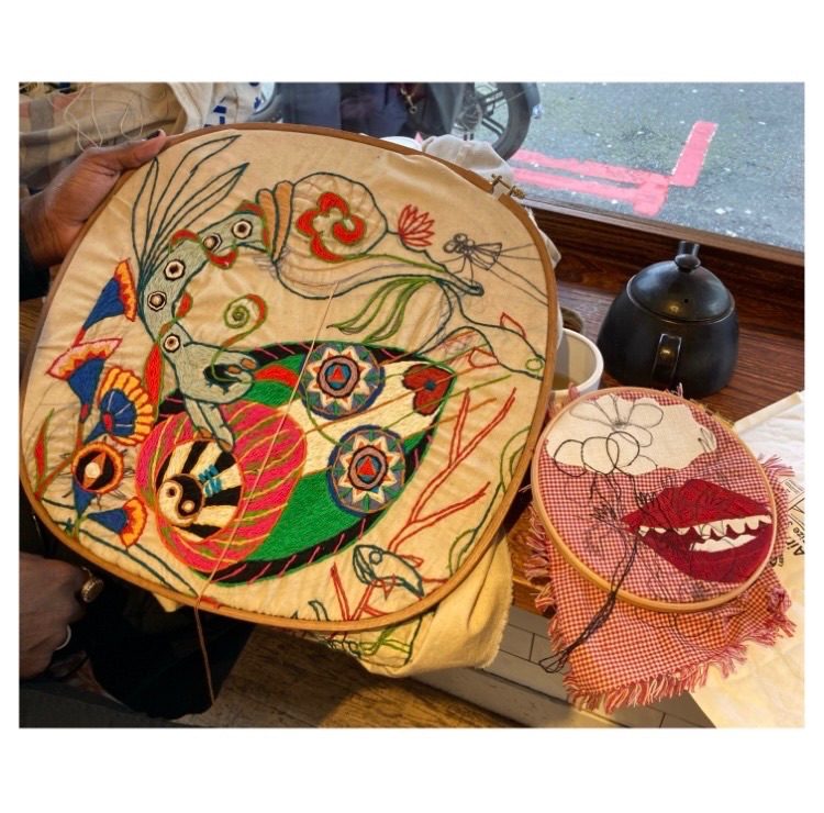 Artists in a cafe with their embroidery hoops