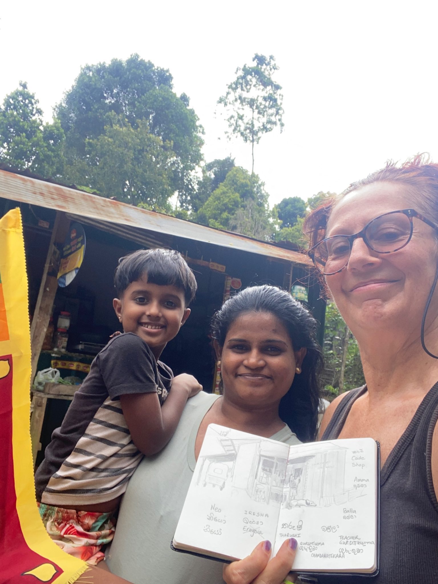 This work documents an encounter that took place while I sat and drew a small local shop in Sri Lanka on Independence Day. As I drew, members of the family who run the shop gradually gathered around me. We did not share a spoken language, but the act of drawing created a shared focus.  I drew objects from the space, including their dog, and asked for the Sinhala word. Family members spoke the word aloud while I wrote it down phonetically, making mistakes and being corrected. They then showed me how to write the word in Sinhala script, clapping and laughing as I learned slowly. The pencil moved back and forth between us.  The drawing did not represent this interaction so much as enable it. Through visible slowness, uncertainty, and not-knowing, drawing functioned as a quiet social act, allowing trust, proximity, and exchange to develop without explanation or shared language.