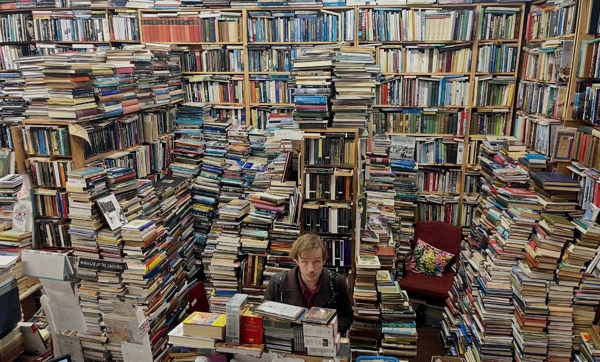 Photography of a man surrounded in piles of books