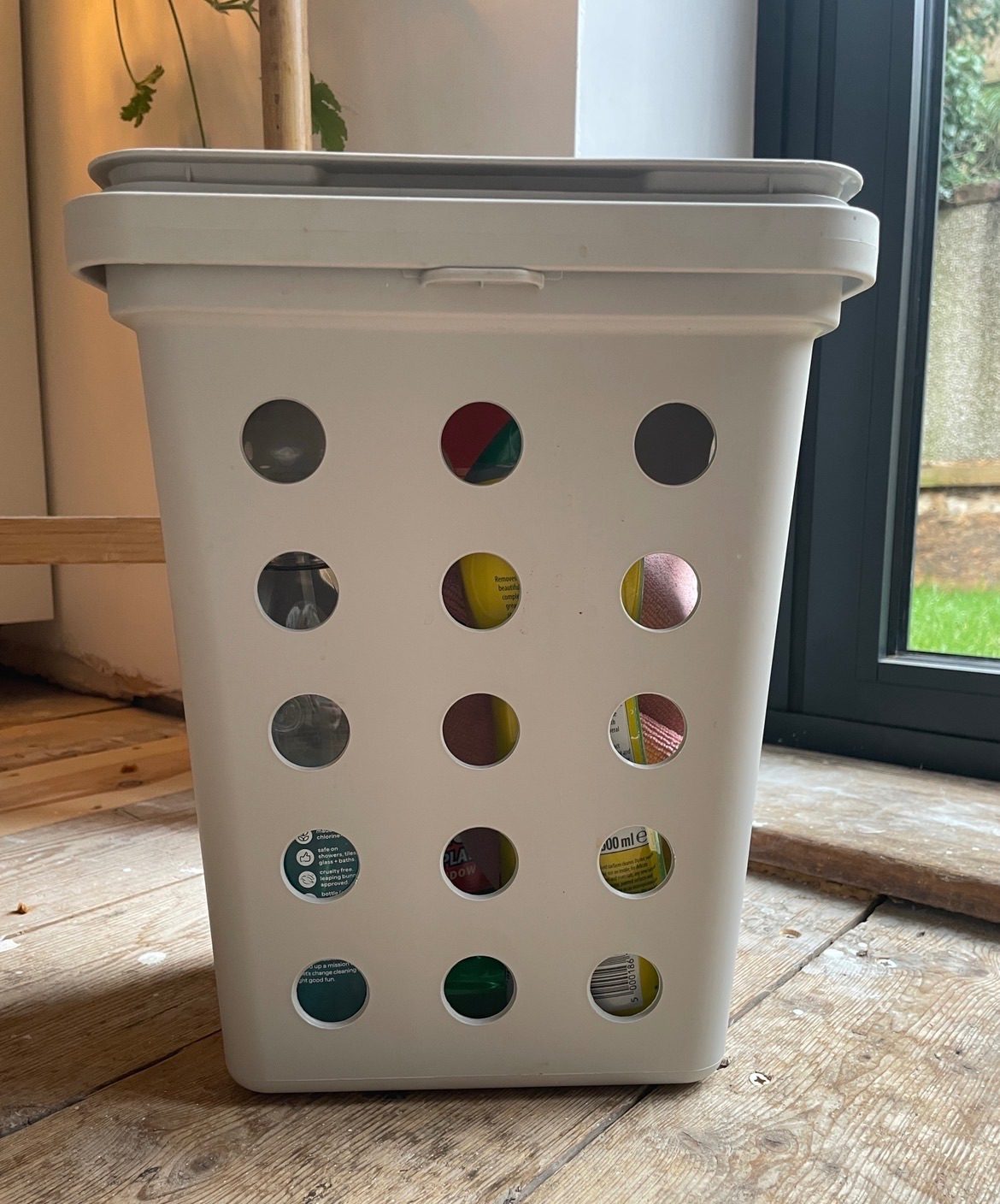 A photo of a bin with holes in it holding cleaning supplies