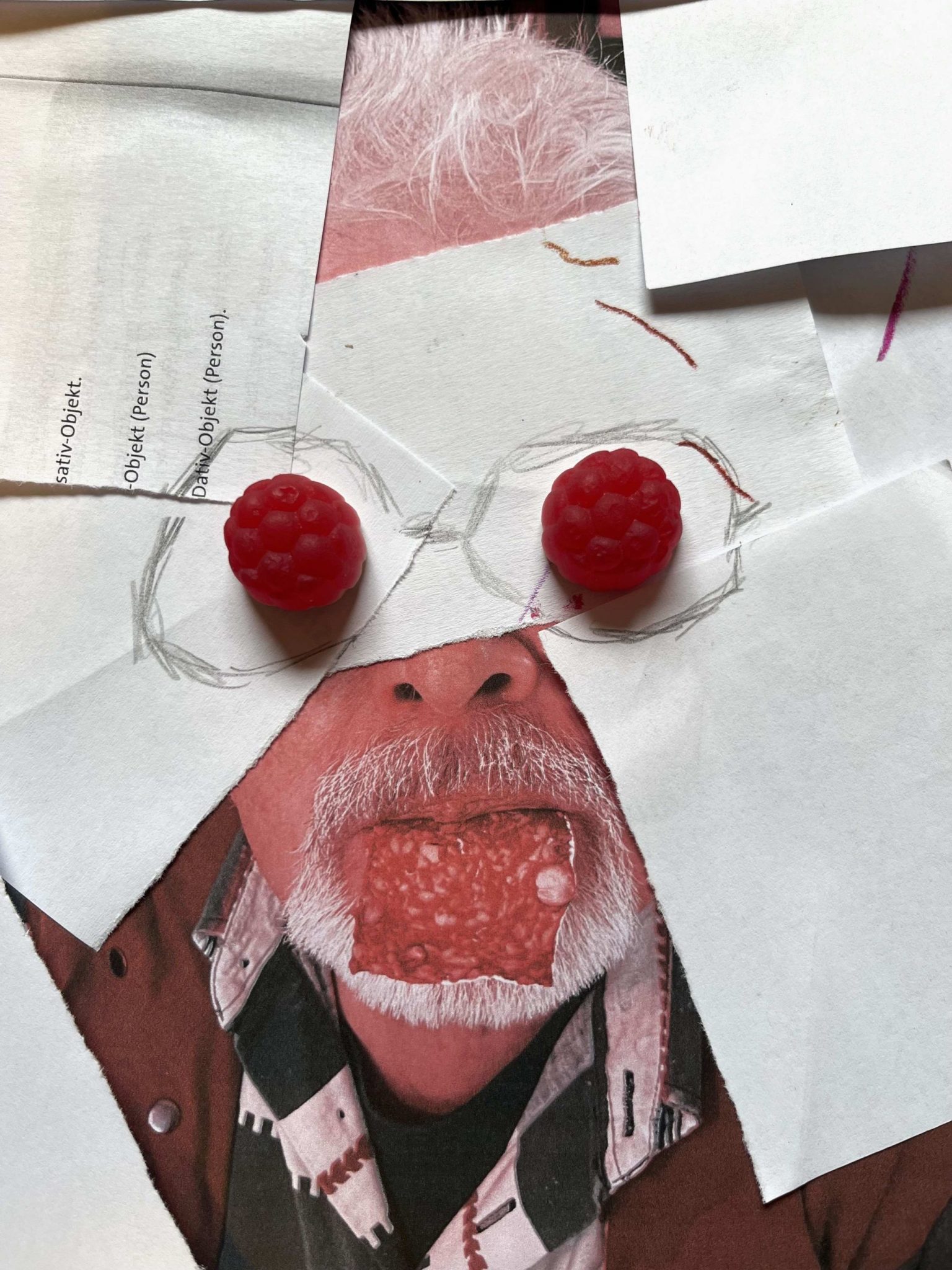 I took a photo of a man and partly covered it with scraps of paper and jelly babies. The picture now shows partly the portrait of a man with a white full beard. A slice of salami is hanging out of his mouth. The upper part of the face is covered, only on top a shock of white hair seems to be protruding. Under the face the man's shirt with a colourful pattern and parts of a waistcoat are visible. The lower part of the nose is visible, too, but its upper parts and the eyes are covered with white and not-so-white scraps of paper. Two red jelly babies take the places of the eyes. I drew a kind of glasses around the jelly babies.