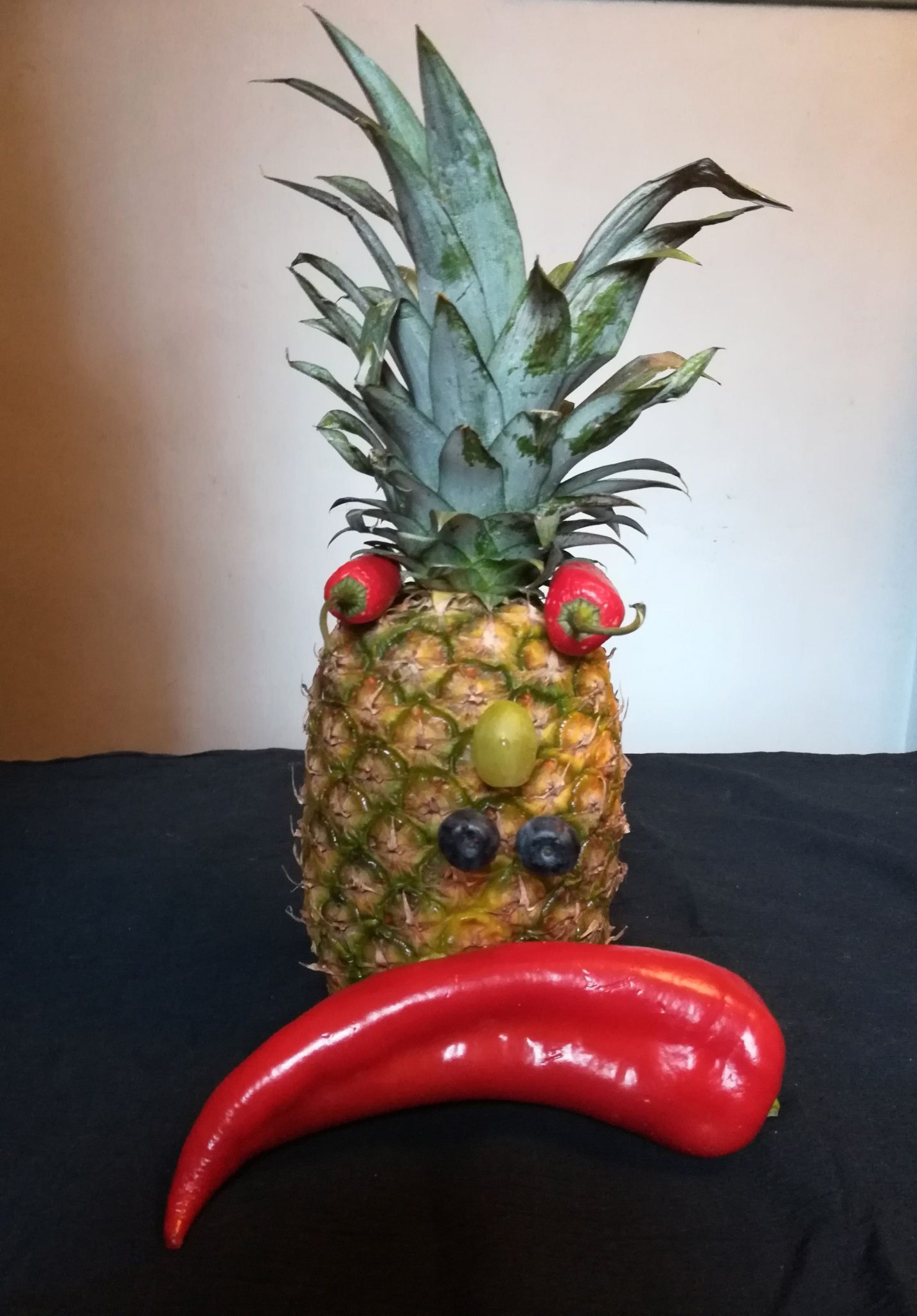 Pineapple with chile pepper eyes, grape nose, blueberry nostrils and big red pointy pepper mouth