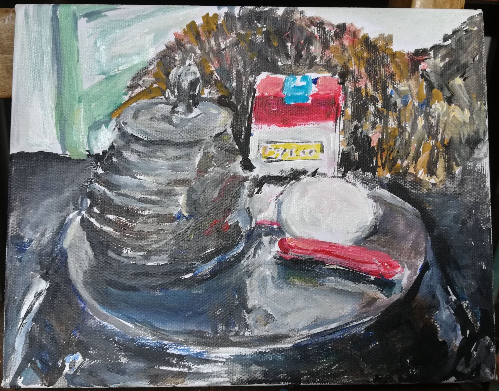 Cast iron teapot,  stallion candy cigarette pack leaning on white egg, red penknife in front on upturned paella dish, omnipresent tortoiseshell cat looming behind on black cloth, green chair in background. Mediem: mostly acrylics with a dab  of water based oils