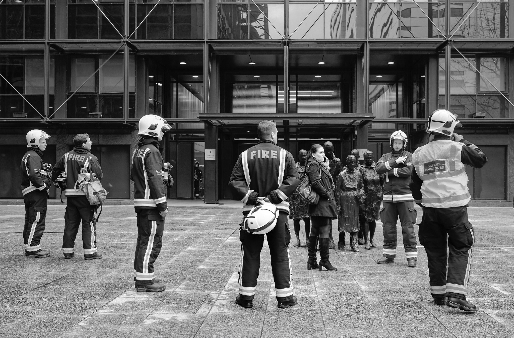 Black and white image of a set of statues and firefighters in Broadgate City of London