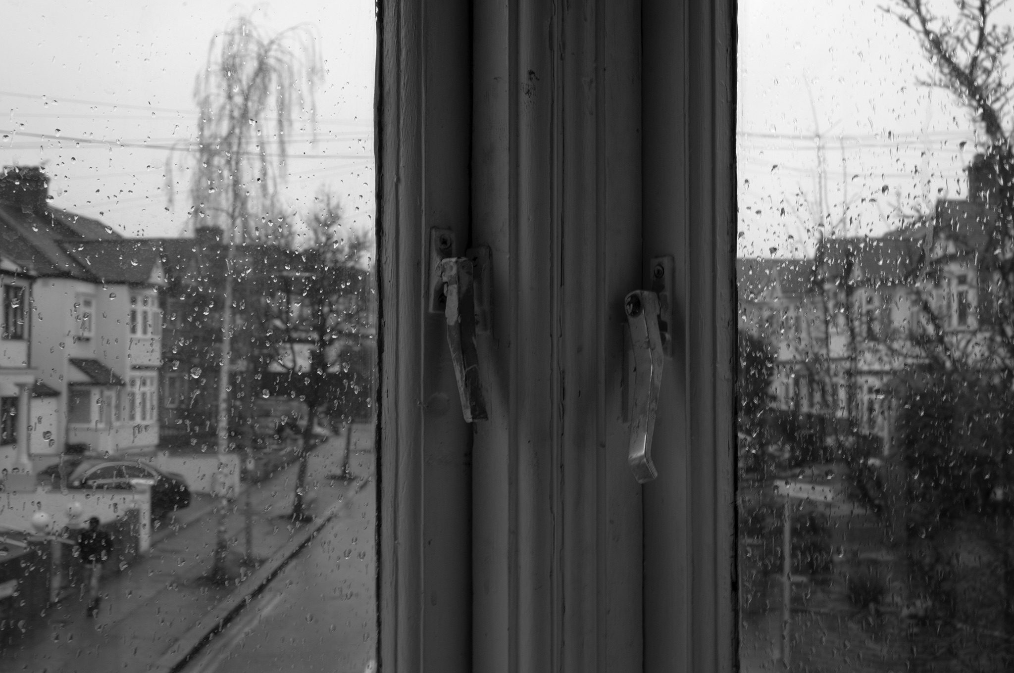 Rainswept street form inside looking out with the window also covered in rain, image in Black and White