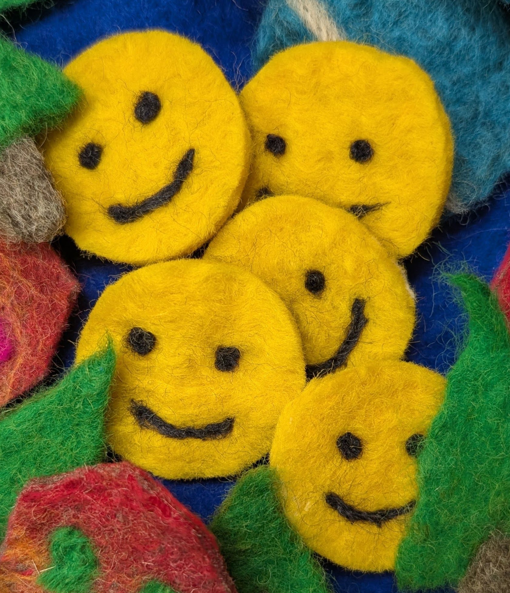 felted smiley faces surrounded by other felted items