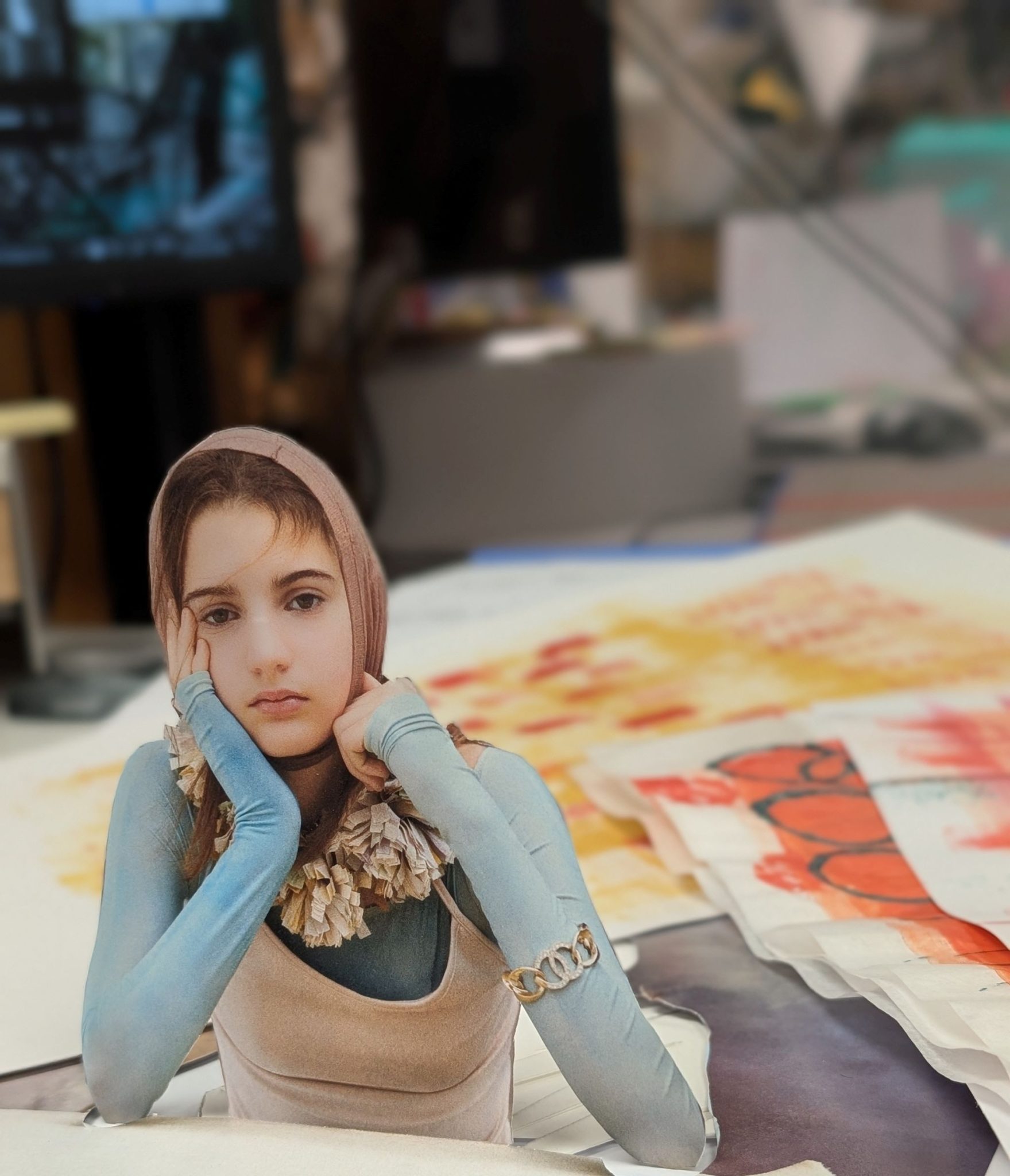 lack and white image of sad looking girl with head propped up on her hands against a backdrop of collage papers