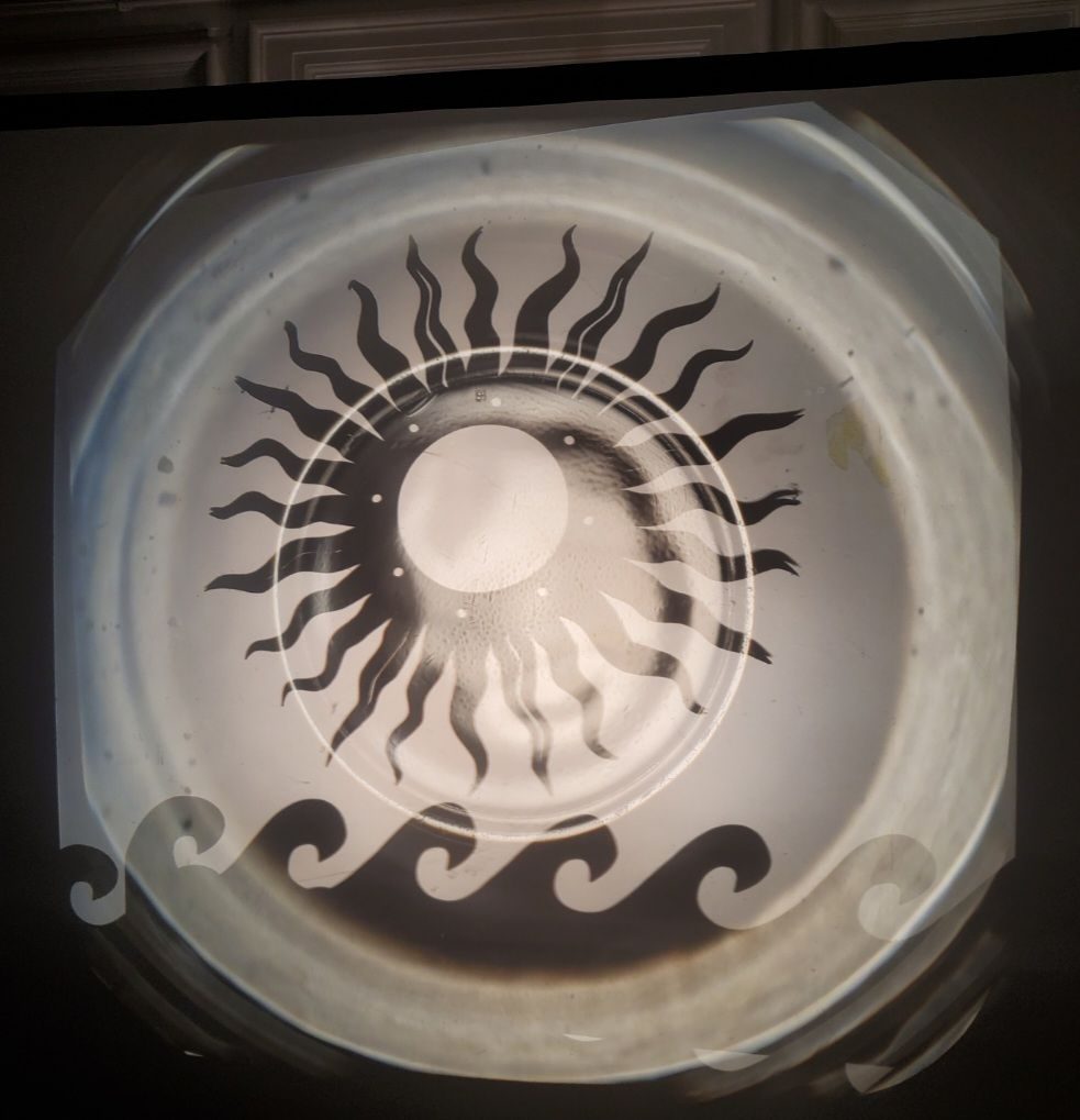 A photograph of shadow puppetry, showing a sun and waves of the sea