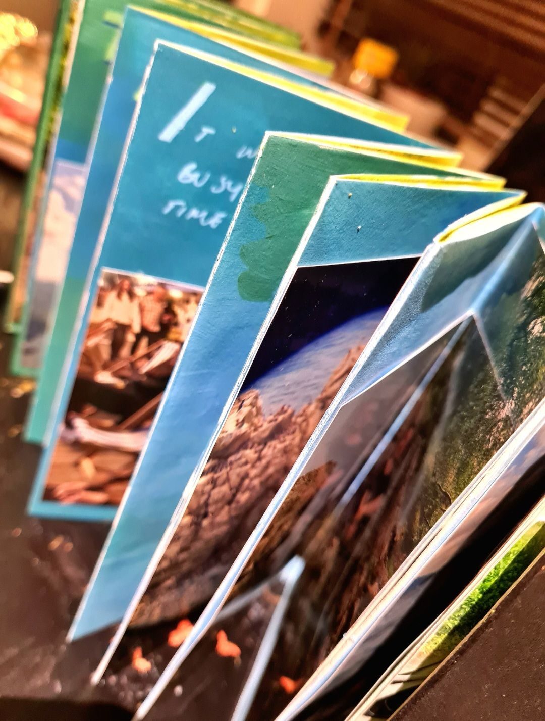 A photograph of a concertina sketchbook illustrated with photos, painting and writing.