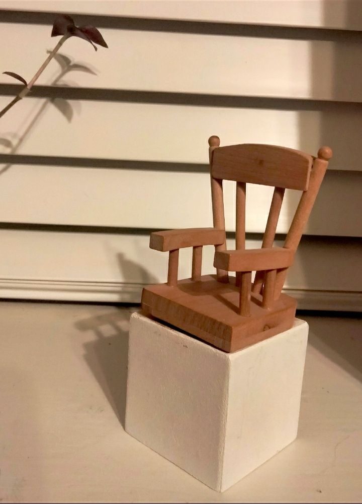Dolls house chair on white wooden block