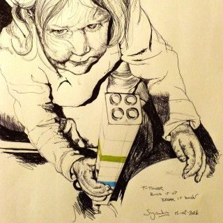 Pen drawing of Tamara building a tower out of lego. All black and white except for one green block and one blue block. Child viewed from above.