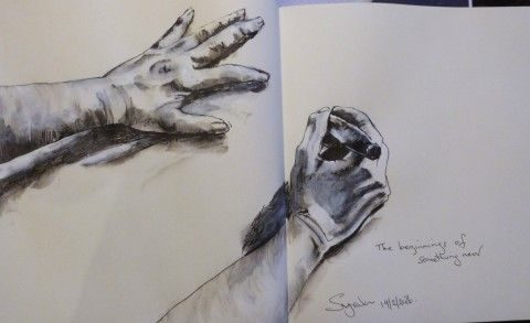 black and white ink drawing of left and right hands and part of each arm, from above. Right hand is about to start drawing.