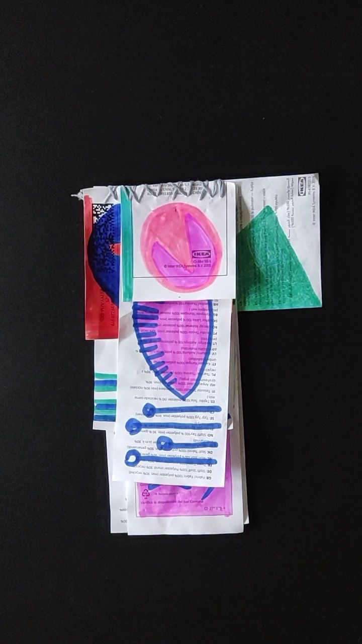 video: two hands in black gloves are turning the pages of an artist's book made of IKEA labels with abstract drawings on them