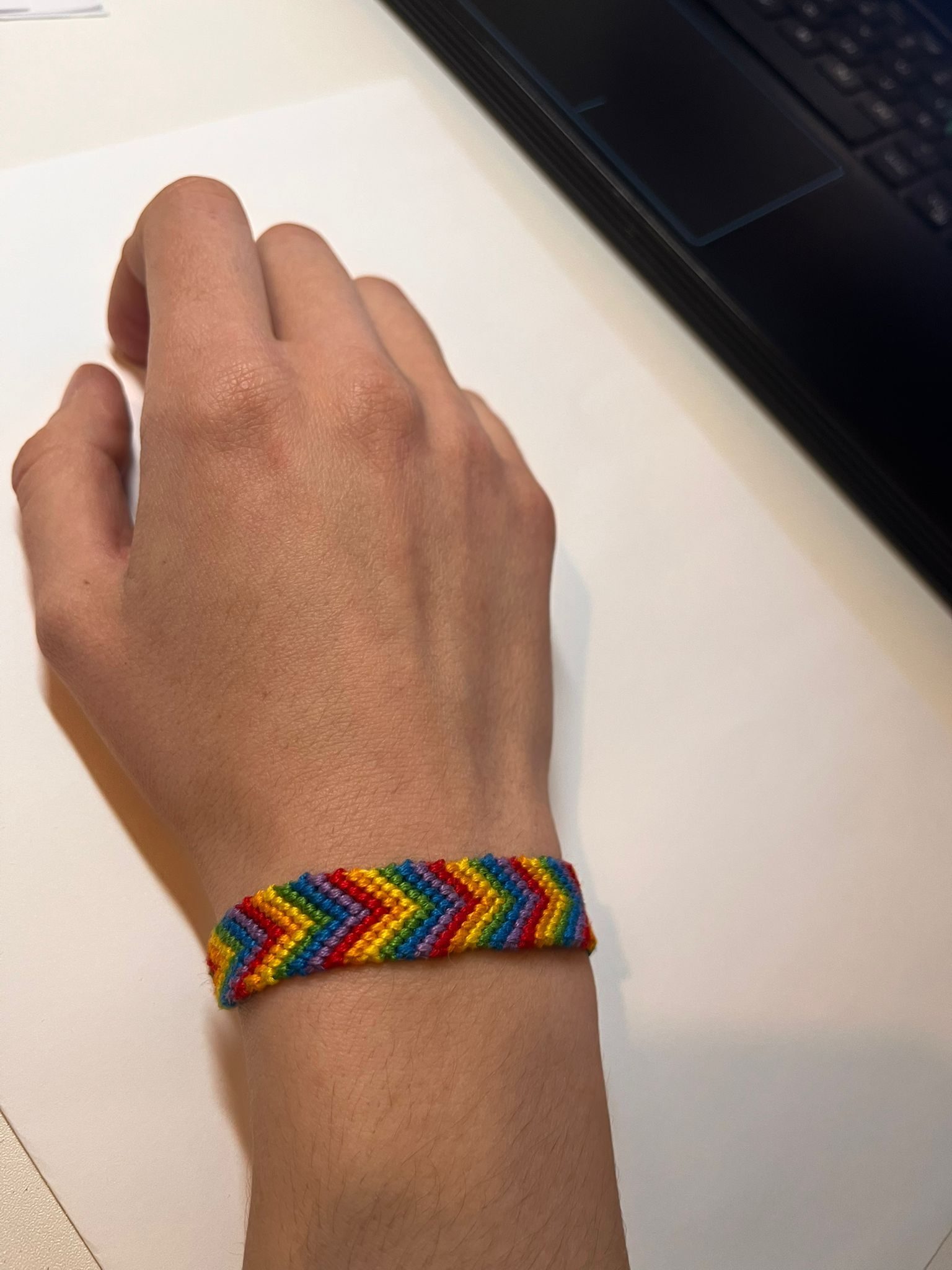 A rainbow v-shape friendship bracelet wraped around the right hand side.