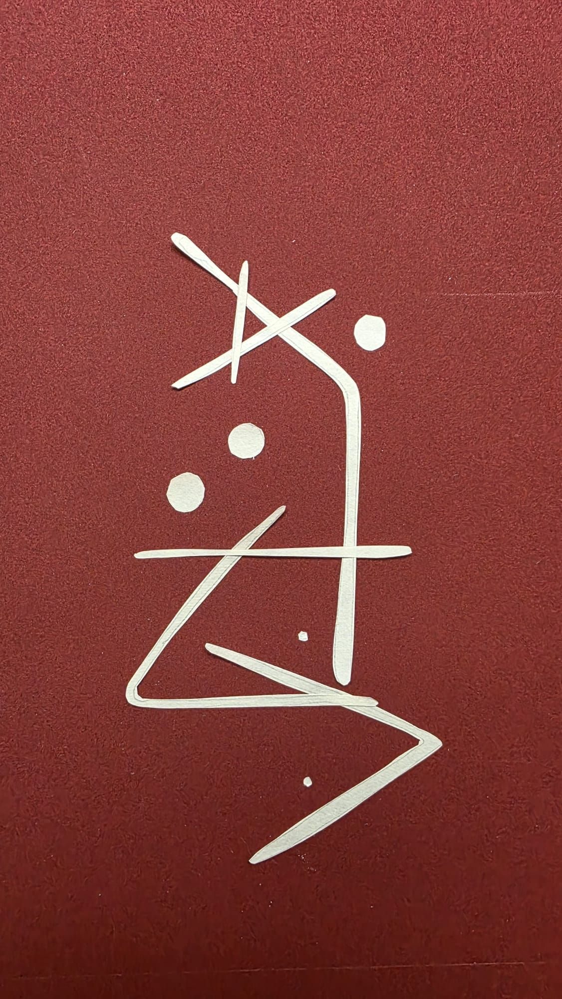 Cut outs from a stencil, arranged on a textured red ground