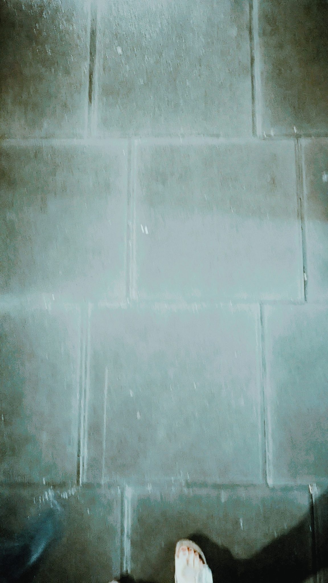 concrete tiles (of a pavement), hints of a foot at the edge of the picture, all in a grey blueish colour