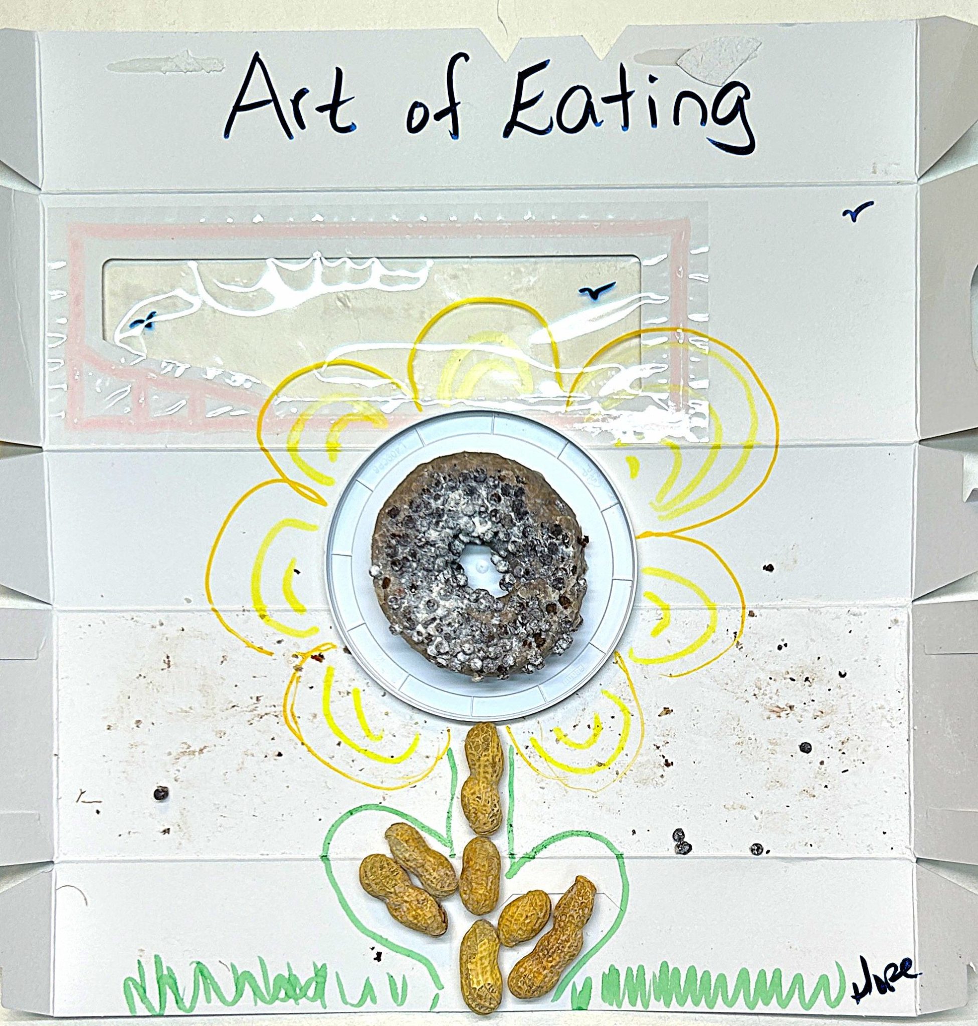 a marker drawn flower made with a donut center and peanuts stem and leaves