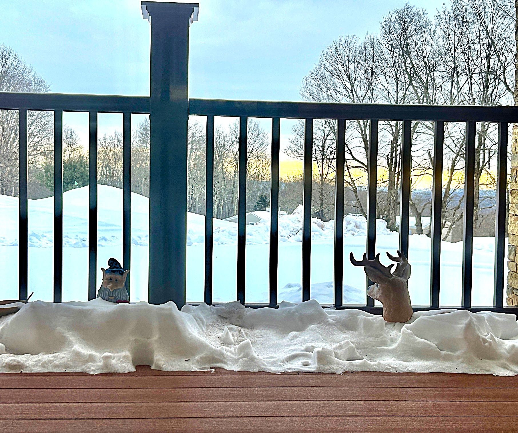 view of snow and two gnomes on a snowy front porch