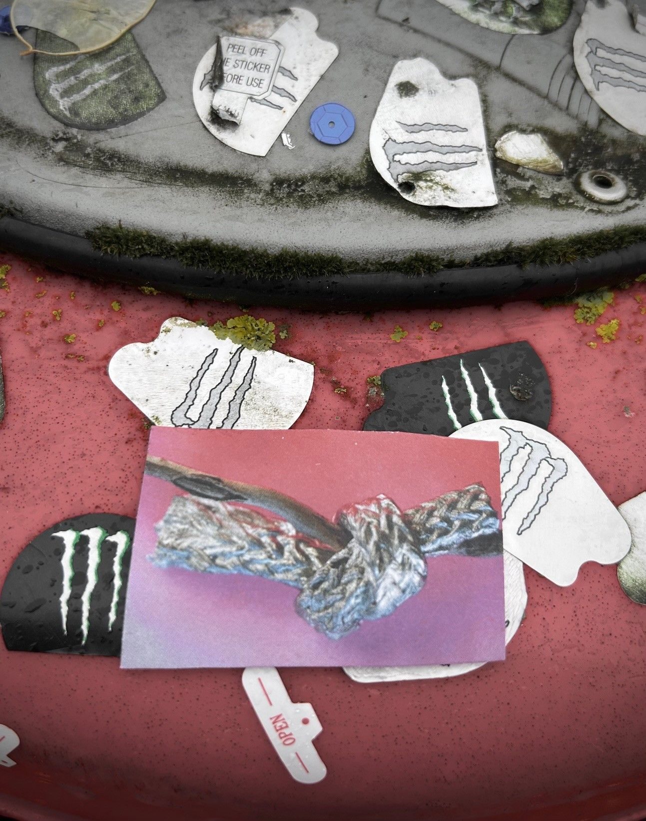 the top of a bin that has lots of randomly placed monster drink stickers. i placed a small photo of a sculpture of a knot round a stick