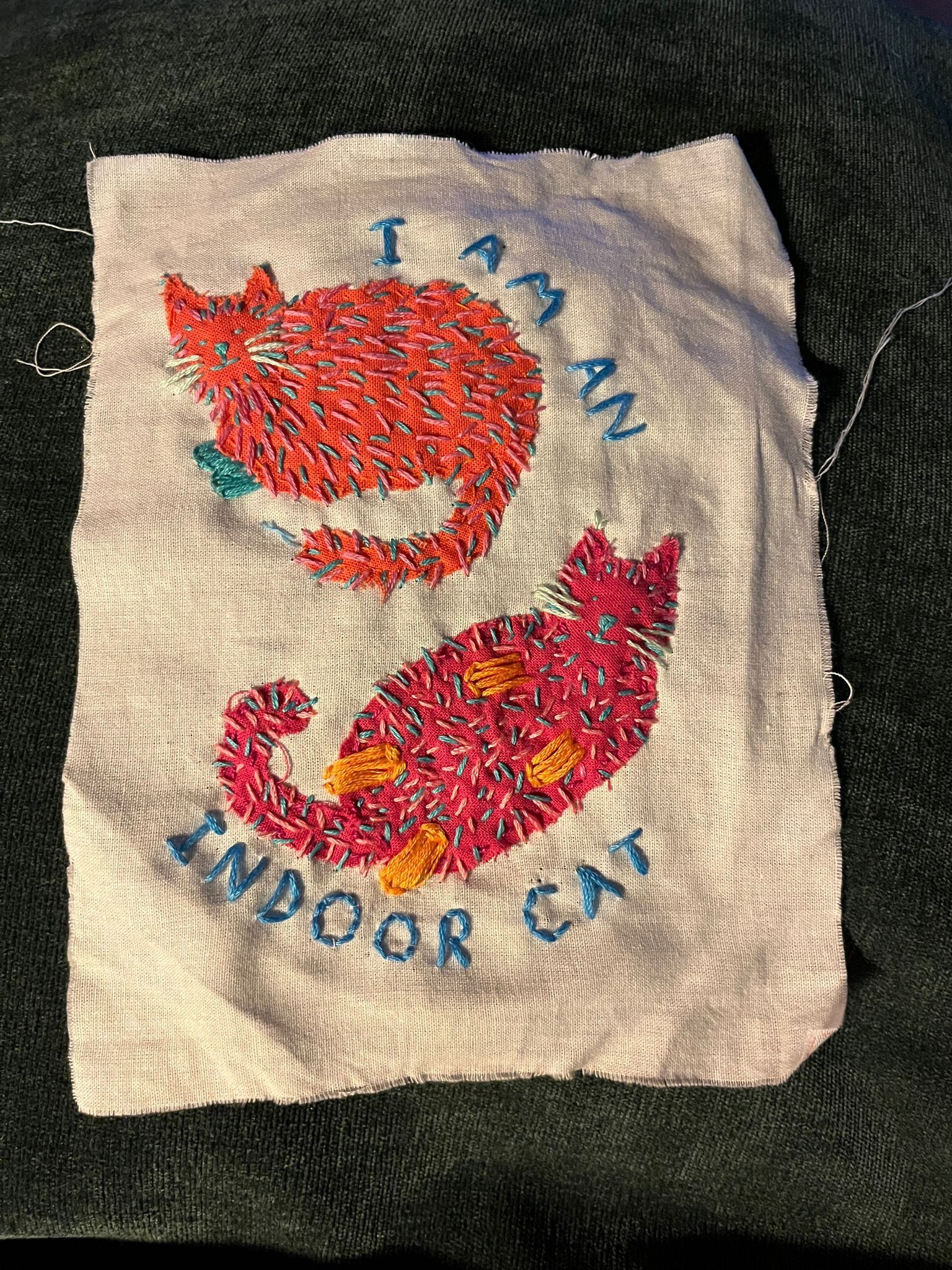 Embroidery of two cats with letters spelling “I am an indoor cat”