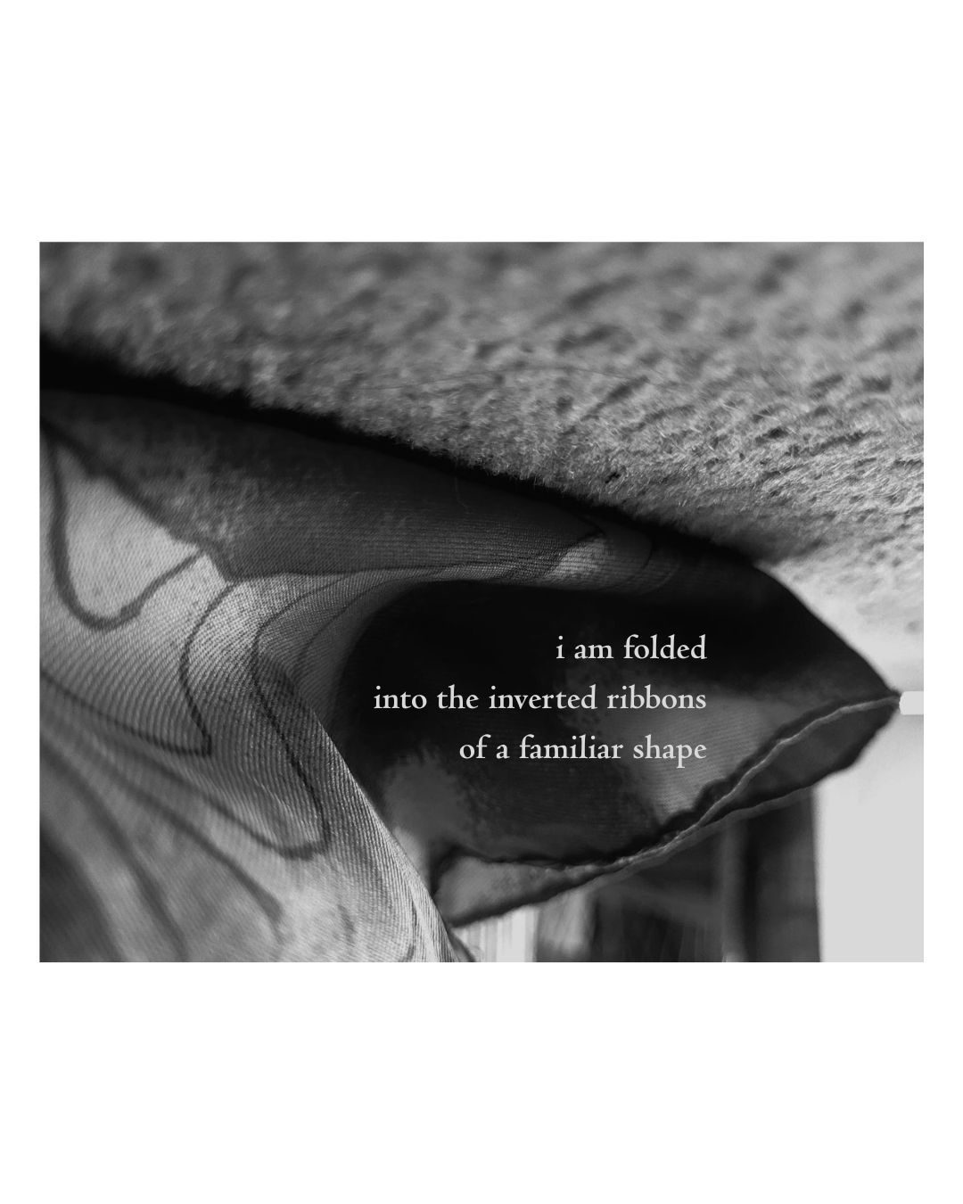 an inverted close up photograph of a scarf on the carpet with a poem overlaid that reads: i am folded into the inverted ribbons of a familiar shape