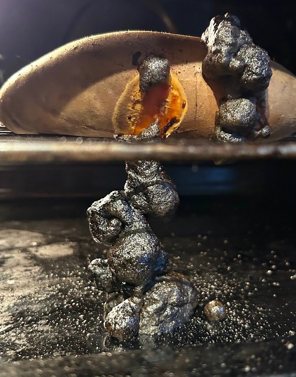 Sweet potato in oven with a black substance that looks like foam coming out of it
