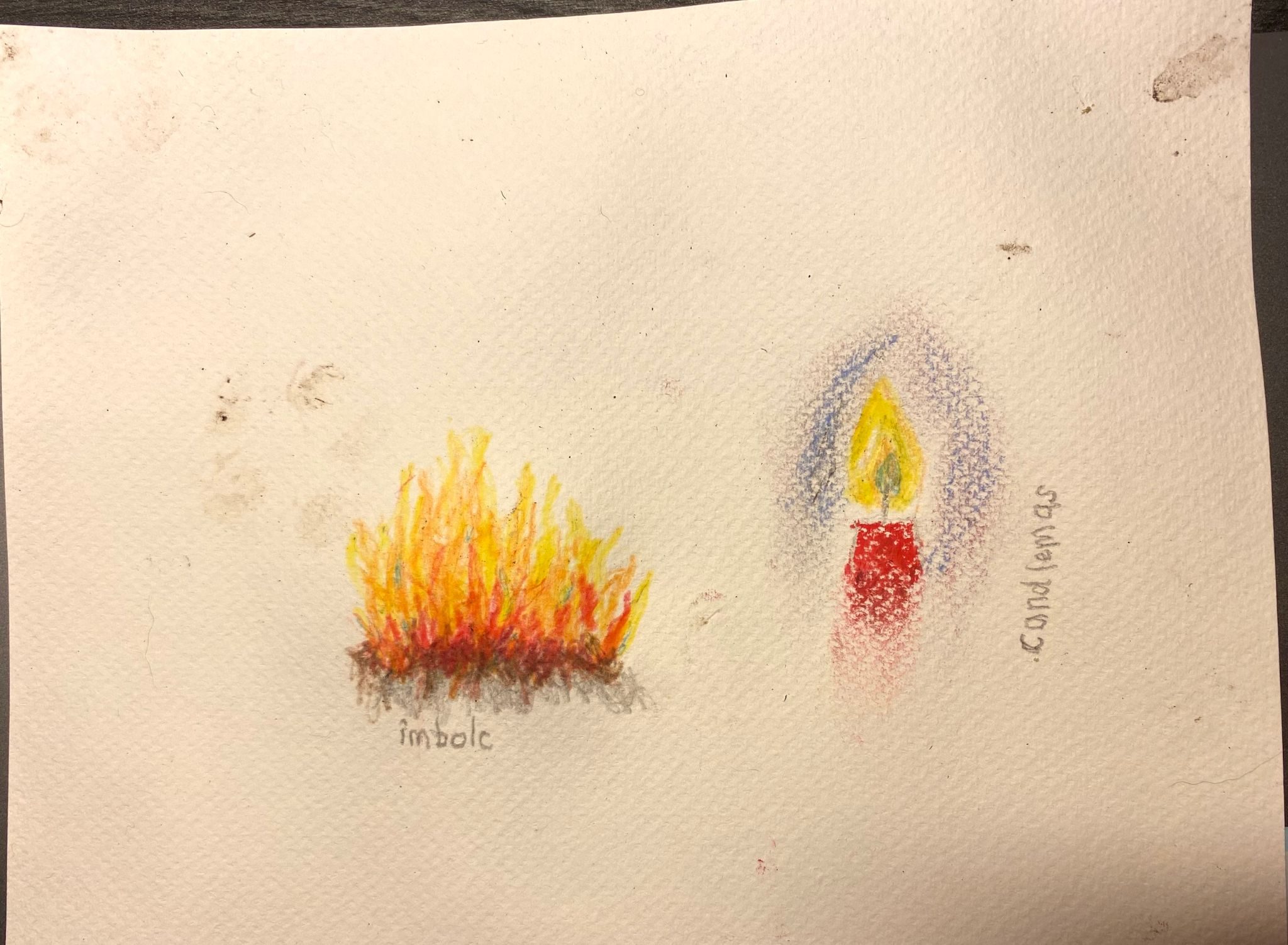 The same sheet of paper with yesterday's drawing and some more dark smudges. Alongside the fire image is a drawing of a candle flame, blue in the centre and yellow around, and the top of a red candle that fades down the page. There is purple-blue shadow around the flame. The word 
