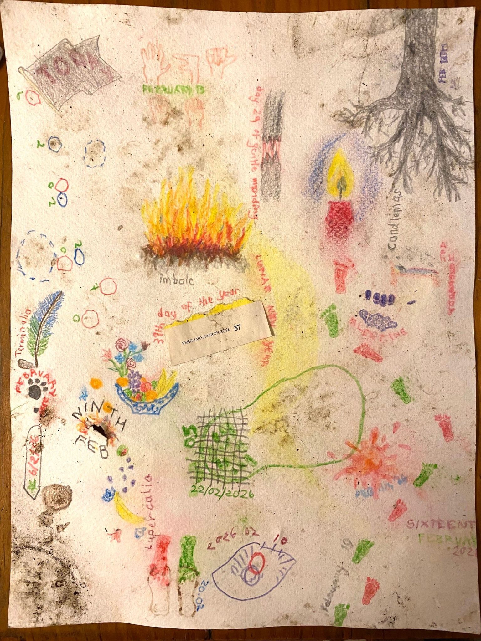 The same drawing as yestereday. A dark quarter circle ring has appeared above the dark marks in the bottom left corner. On the left side, above the paw print and next to the circled dots, there is a feather coloured blue shading to green, resting next to a small brown-grey pebble. The word 