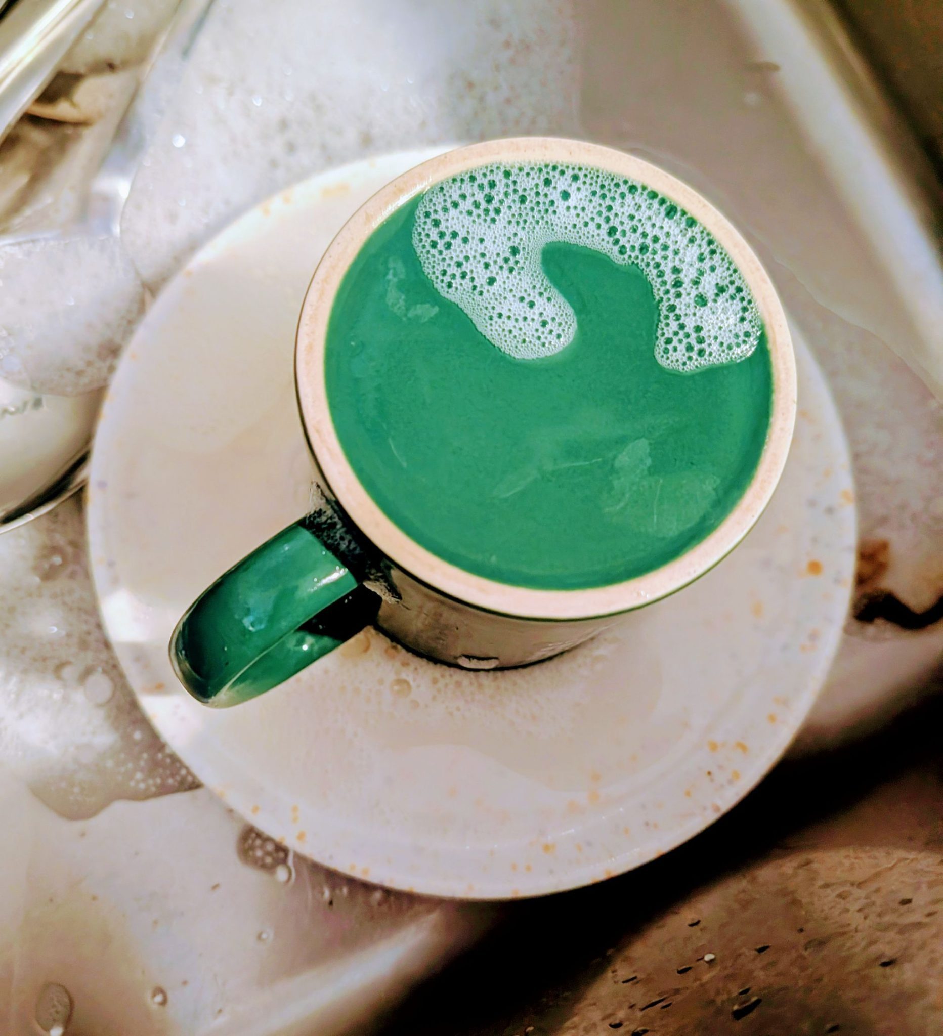An upside green coffee cup with washing liquid cup resembling coffee froth
