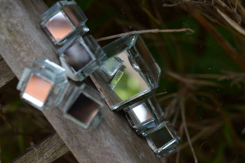 a photo showing seven small cubes made of glass, attached to a wooden surface, reflecting each other