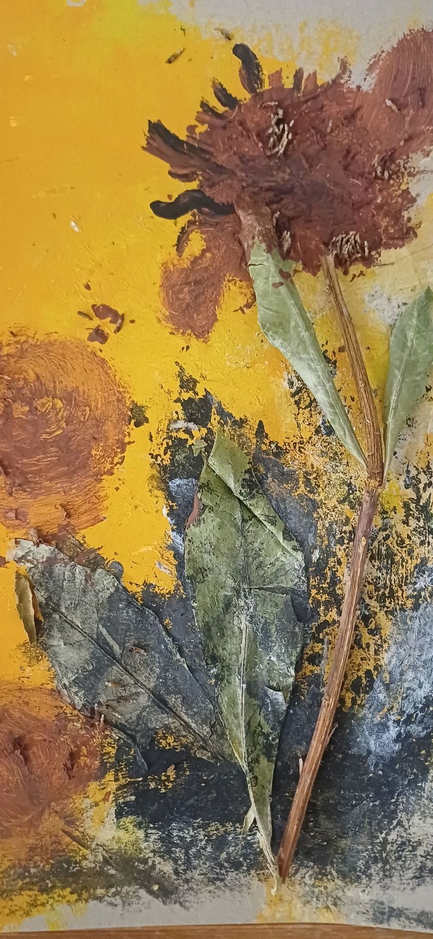dried flowers encased in paint attached to a cardboard covered in yellow, black and red paint