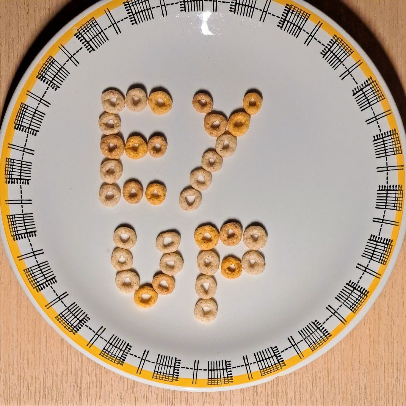 A round white plate with pieces of cereal hoops spelling out 