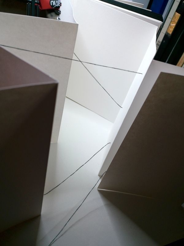 abstract drawing with black thread, stretched between different pages of a concertina book