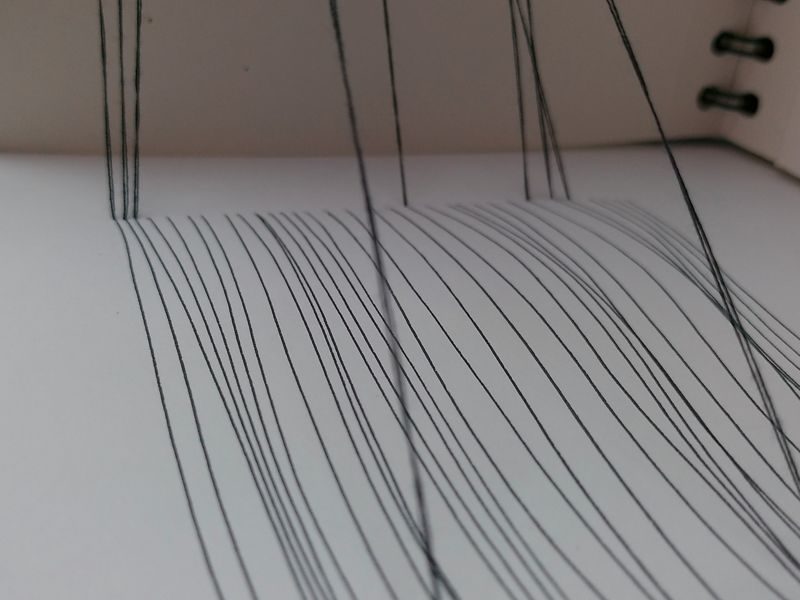 abstract drawing with black thread and black pen, view from the ground drawing in black pen, black thread stretching from drawing to the vertical page of sketchbook
