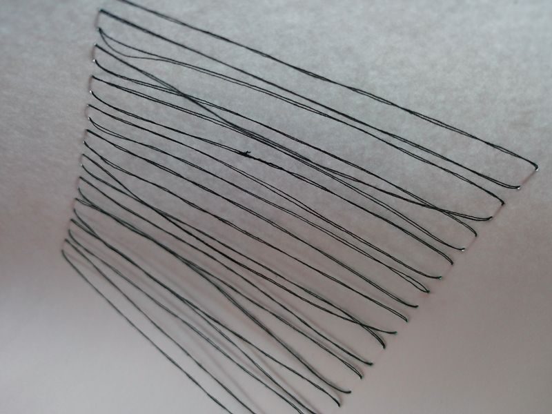 abstract drawing with black thread on white paper, individual threads casting shadow onto the paper, some threads hanging over others