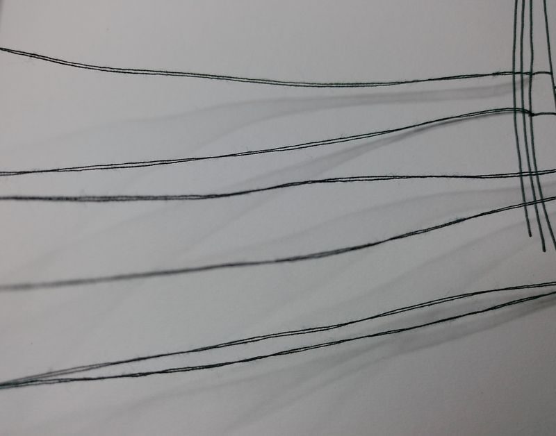 Black thread connecting to a drawing in black pen, casting gentle shadows onto the paper