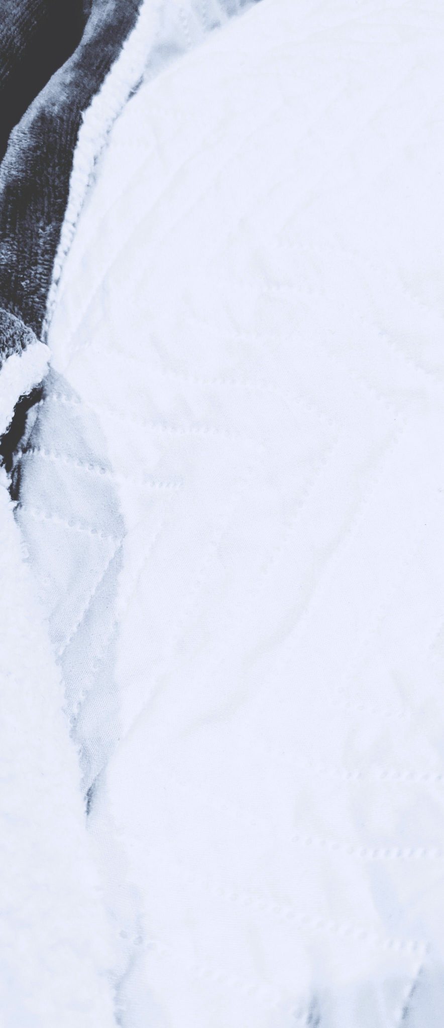 a zoom in on a small part of a duvet, with a small bit of a blanket on the left