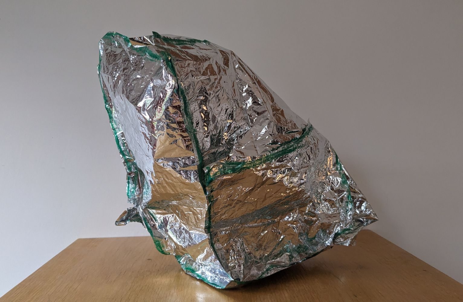 A foil object with green seams on a wooden shelf