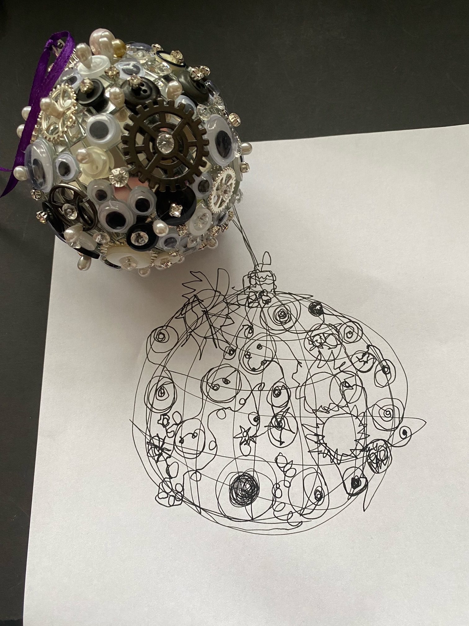 A black pen drawing on white paper of a disco ball covered in buttons and cogs and googly eyes
