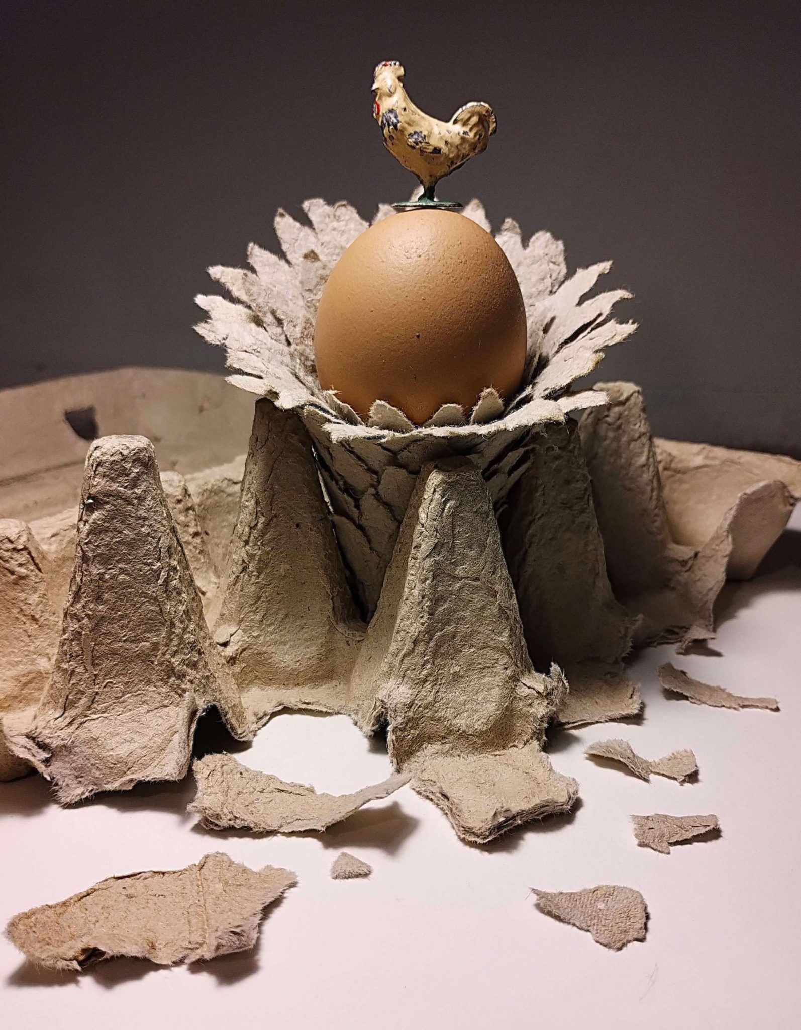 this is a small sculpture made from an egg box of a flower with an egg in the center, topped with a tiny lead chicken