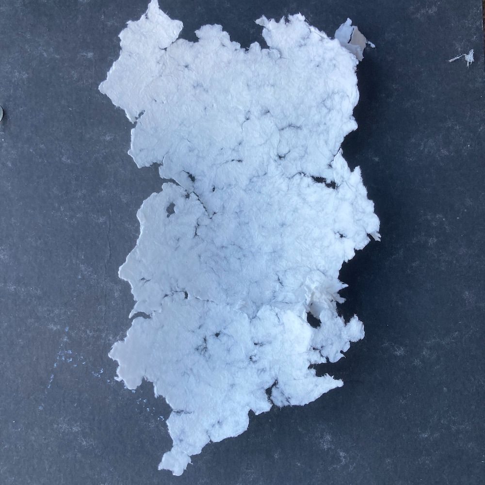 a small white paper landscape sculpture study sits on a dark grey background