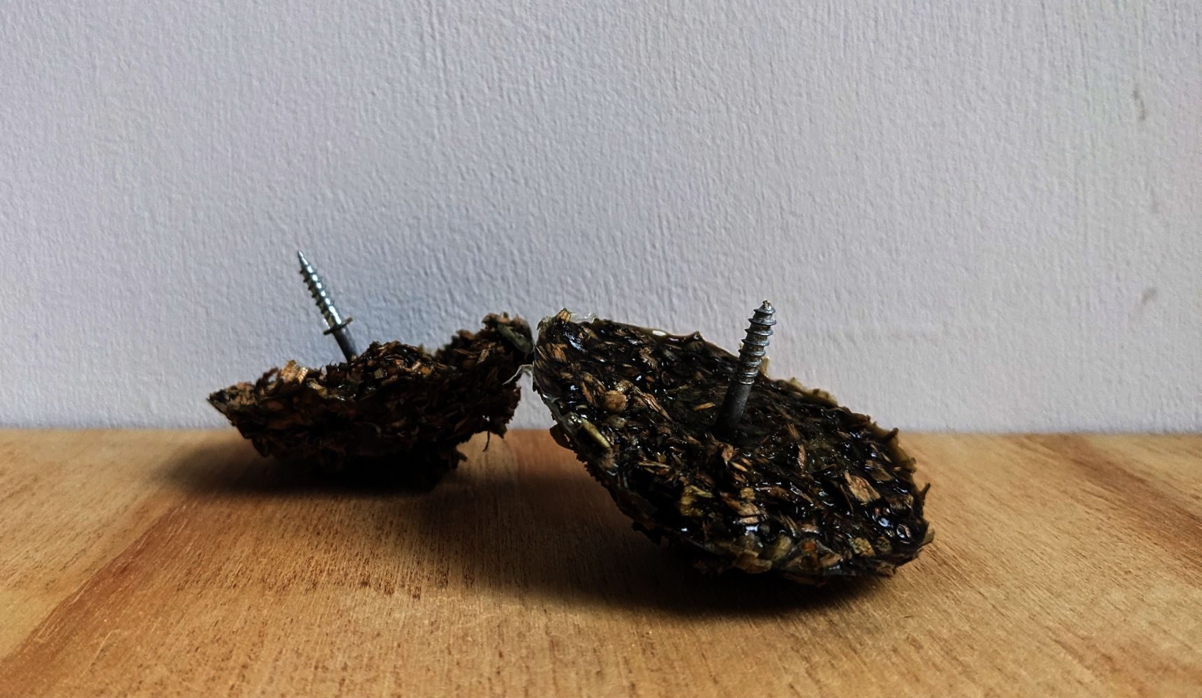 two dome head objects made of green sawdust with screws emerging