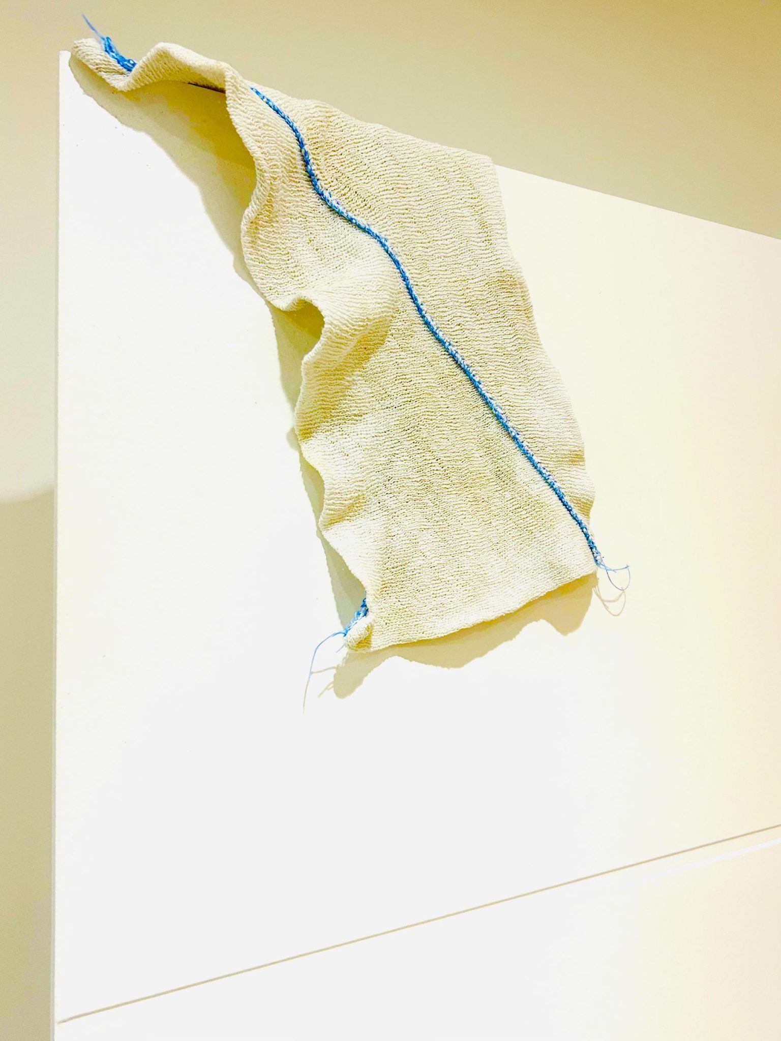A photograph of a dish cloth draped over the top of a door within the interior of a kitchen